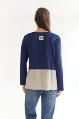 Remera de manga larga en color azul, con diseño asimétrico que presenta una franja lateral en color beige. Posee cuello redondo, corte más corto en la parte delantera y más largo en la trasera, con aberturas laterales y detalles de pespuntes visibles.