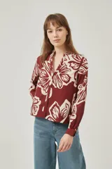 Camisa de poliéster con estampado floral en tonos bordó y crema, de corte holgado, cuello mao y cierre frontal con botones.