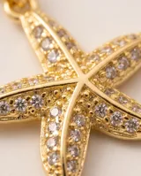 Collar de cadena fina eslabonada en color dorado con dije en forma de estrella de mar, cubierto de circones brillantes.
