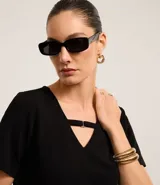 Blusa negra de crepé con cuello en V y mangas cortas. El cuello posee una tira horizontal unida por una pequeña hebilla metalizada.