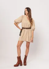 Vestido corto color beige, de corte oversize, con escote en V y mangas globo. Incluye cinturón marrón con hebilla dorada.