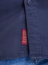 Camisa de manga larga color azul marino, con cuello clásico y cierre frontal de botones.