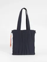 Cartera tipo shopper de color azul marino con diseño matelaseado de líneas onduladas. Cuenta con doble asa de hombro y un detalle de tiras decorativas multicolores en uno de los laterales.