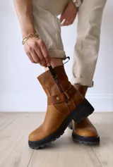 Bota de cuero color marrón con suela de goma negra, cierre lateral y pulsera desmontable con hebilla.