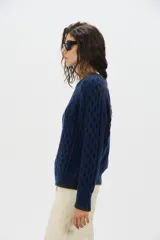 Sweater de punto de mohair color beige, con cuello redondo, mangas largas y detalles de terminación en color negro en el cuello, puños y ruedo.