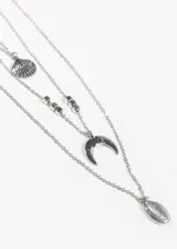 Conjunto de cuatro collares plateados de diferentes largos. El primero es una cadena simple, el segundo tiene un dije de concha, el tercero tiene cuentas y un dije de media luna, y el cuarto tiene un dije de caracol.