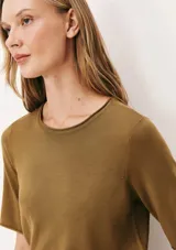 Blusa color verde oliva de tejido de punto, con cuello redondo y mangas cortas. Corte recto.