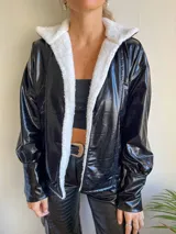 Campera negra de cuero sintético con interior de corderito blanco, corte holgado y mangas largas con puños elásticos.