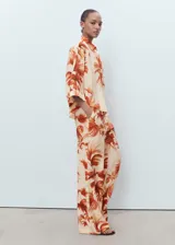 Pantalón tiro medio de tejido fluido con diseño recto y largo, con estampado de palmeras, bolsillos laterales y forro interior.