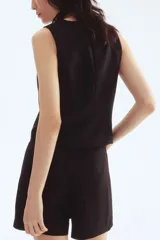 Chaleco negro, corto, con escote en V pronunciado y cierre frontal de tres botones oscuros. Presenta pinzas moldeadoras para un calce entallado y está forrado.