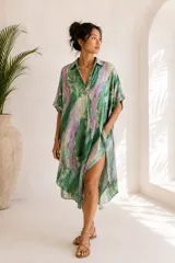 Túnica midi de seda con estampado estilo tie-dye en tonos verde, lila y blanco. Cuenta con cuello camisero, escote en V profundo, mangas cortas amplias, bolsillos laterales y calce oversize.