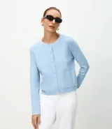Cardigan de punto color celeste, con cuello redondo, cierre frontal con botones y dos bolsillos delanteros. Presenta mangas largas con puños y escote con acabado canelado.