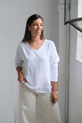 Remera de algodón color blanco, con cuello en V, mangas largas y corte holgado con costuras visibles en el ruedo.