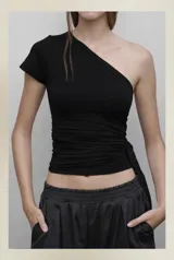 Top negro ajustado al cuerpo, con diseño asimétrico de un solo hombro y manga corta en un lado. Presenta frunces laterales que permiten ajustar el largo y el calce.