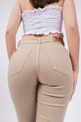 Pantalón tipo oxford de tiro alto, color beige, con diseño de cinco bolsillos y cierre frontal con botón y cremallera.