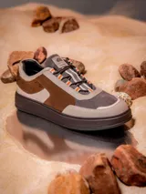 Zapatillas Hush Puppies edición limitada inspiradas en Luke Skywalker, con diseño en tonos tierra, beige y marrón. Presentan una combinación de cuero y descarne, con detalles de Star Wars grabados en el lateral y en la lengüeta, y cordones con detalles en naranja.