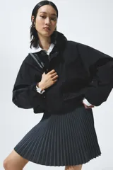 Minifalda plisada de corte evasé, en color negro, con cintura elástica de ribete oscuro y sutiles líneas contrastantes.