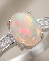 Anillo de plata con ópalo blanco ovalado en el centro, flanqueado por pequeños detalles de circonias en el aro.