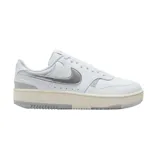 Championes Nike Gamma Force de diseño urbano, con base blanca y detalles en plateado metalizado en el logo lateral y el talón. Presenta una suela de plataforma en tono crema con acabado gris en la parte inferior.