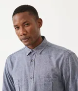 Camisa de manga larga color celeste con textura, cuello camisero, cierre frontal con botones y dos bolsillos de parche en el pecho.