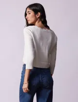 Cardigan tejido en hilado fino color blanco, marca Cable & Gauge. Abertura central con broche interno y terminación ondulada.