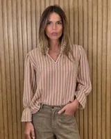 Blusa de algodón color azul, de corte suelto, con mangas largas abullonadas y cuello con volados y escote en V.
