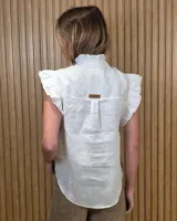 Musculosa de jean celeste sin mangas, con cuello alto fruncido, cierre frontal con botones y detalles de volados en las sisas y a lo largo de la botonera.