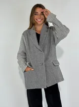 Saco gris con solapas de muesca, cierre con doble botonadura y mangas largas tejidas a rayas horizontales.