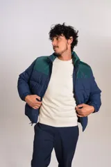 Campera puffer con diseño bicolor, cuerpo en azul marino y canesú superior en verde oscuro. Presenta cuello alto, cierre frontal completo y puños elásticos.