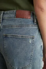 Pantalón de jean estilo wide leg con tiro medio, corte holgado y ruedo deshilachado.
