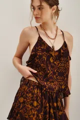 Top de tirantes finos con escote en V y detalle de volados en el borde. Presenta un estampado abstracto en tonos marrones y ocres, con un diseño fluido y ligero.