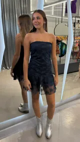 Vestido corto strapless de encaje color azul marino, con diseño ajustado al cuerpo y ruedo con volado semitransparente.