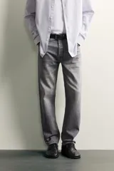 Jeans regular fit de mezclilla negra con efecto lavado, corte recto y tiro medio. Cuenta con diseño de cinco bolsillos y cierre frontal con cremallera y botón.