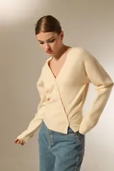 Saco de punto con cuello en V y cierre frontal con botones. Presenta un diseño ajustado al cuerpo, manga larga y terminación acanalada en el ruedo.