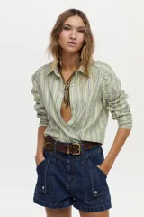 Camisa de lino y viscosa con diseño a rayas verdes y azules, cuello camisero, manga larga raglán con fruncidos y corte cruzado en el frente.