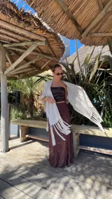 Ruana de tejido de punto color crema con diseño de líneas horizontales caladas y terminación con flecos en el ruedo.