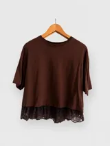 Remera de algodón color marrón, de corte holgado y diseño liso, con un volado de encaje en el ruedo inferior.