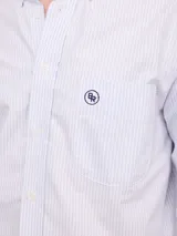 Camisa de corte regular confeccionada en tejido Oxford de algodón, con diseño de rayas verticales finas. Presenta cuello abotonado, cierre frontal con botones y un bolsillo en el pecho.