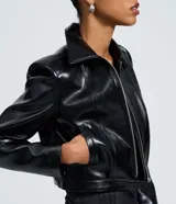 Campera de poliuretano con acabado liso, corte ajustado y largo corto. Presenta cuello estructurado, mangas largas, cierre frontal con cremallera metálica y recortes verticales que estilizan la silueta.