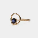 Anillo de oro 18k con diseño minimalista que presenta un zafiro azul engastado en un círculo metálico.