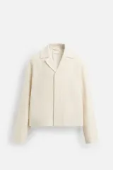 Sobrecamisa de hombre color crema, confeccionada en tejido con estructura, de corte regular fit. Presenta cuello bowling, manga larga y bolsillos delanteros ocultos en costura. Cierre frontal con botonadura oculta por solapa.