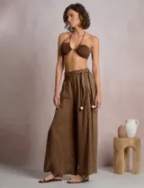 Pantalón palazzo de lino color azul, de tiro alto con cintura elastizada y cinto lazo incorporado con cuentas decorativas en las puntas. Presenta aberturas laterales pronunciadas en las piernas y corte amplio.