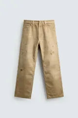 Pantalón straight fit de algodón con efecto lavado y roturas localizadas. Presenta diseño de cinco bolsillos, cierre frontal con cremallera y botón metálico.