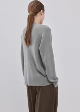 Cardigan de punto gris con cierre frontal de botones, cuello en V y mangas largas.