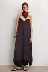Vestido midi color morado oscuro, confeccionado en tejido satinado con efecto plisado o arrugado. Presenta escote en pico y tirantes finos ajustables. El calce es fluido y holgado.