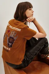 Remera de algodón color marrón con estampa gráfica en la espalda que incluye manos, un ojo y la frase 'Trust your intuition, your fate is in your hands'.