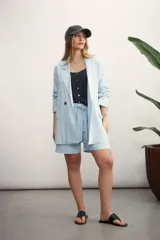 Blazer de mujer color rosa pálido, de corte recto y largo, con solapas de muesca y un solo botón frontal marrón. Presenta bolsillos de parche en la parte delantera y mangas tres cuartos.