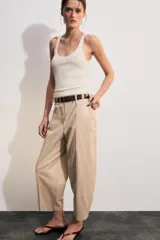 Pantalón tiro bajo color marrón, de corte globo y pernera recta con raya marcada al frente. Incluye trabillas y un cinturón marrón oscuro con hebilla metálica.