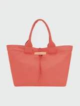 Bolso tipo shopper de gran tamaño, confeccionado en lona resistente color caqui. Presenta un diseño minimalista con doble asa superior y un cierre frontal característico mediante una trabilla de cuero con pasador metálico.
