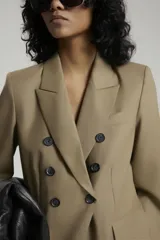 Saco negro de lana con calce entallado, cruzado con botones dorados con pie en delantero y bolsillos sastreros en delantero con tapa.